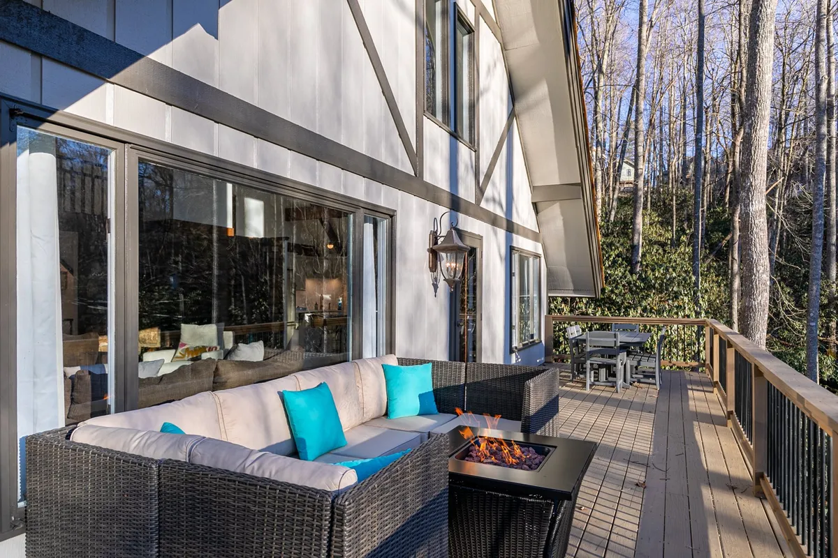 An outdoor seating area arranged around a cozy fire pit, nestled among trees. The comfortable chairs and inviting fire create a relaxed, intimate atmosphere, ideal for evening meals, nightcaps, or dessert under the stars.